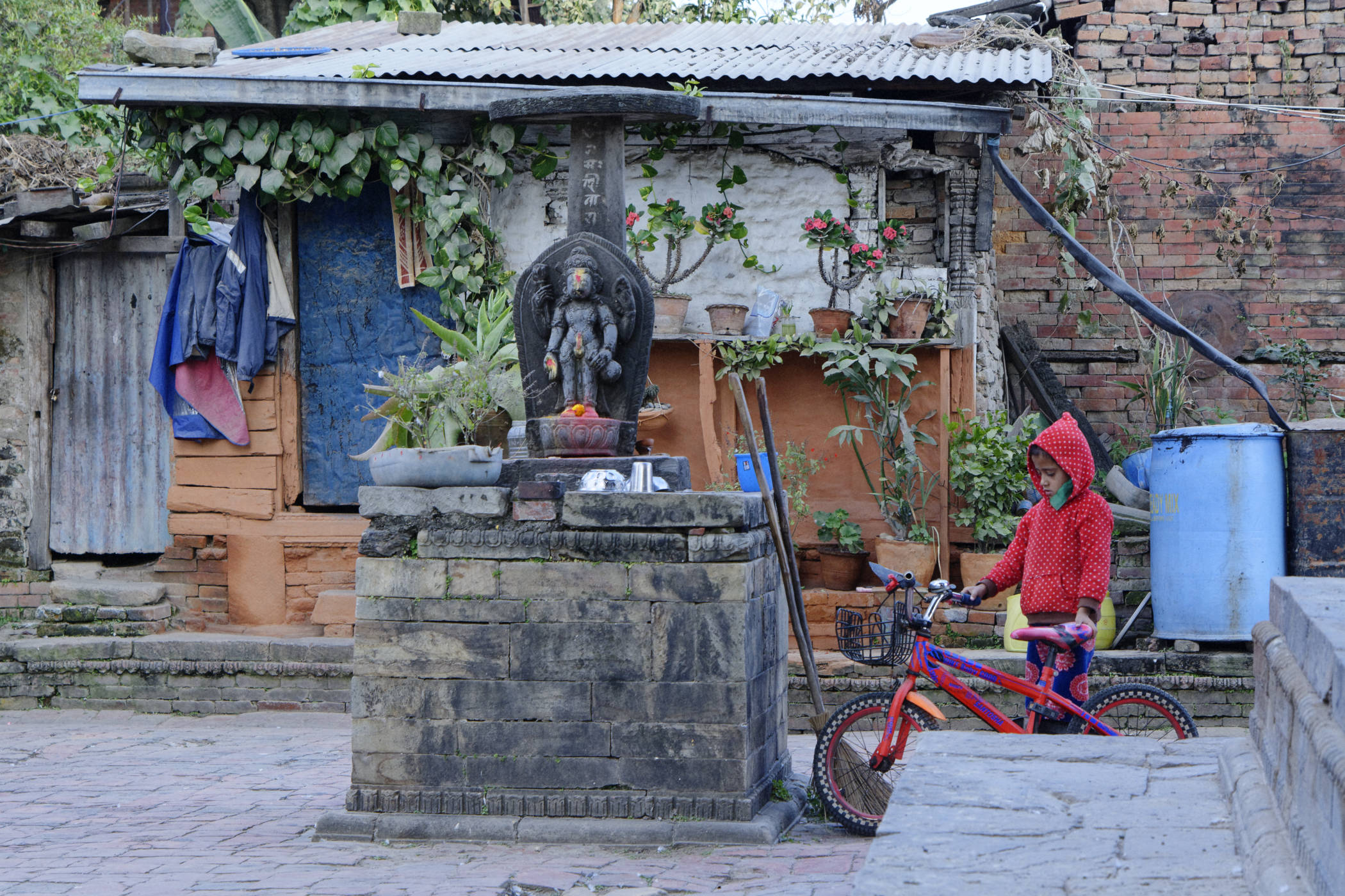 Sculpture bouddhiste et fillette au vélo