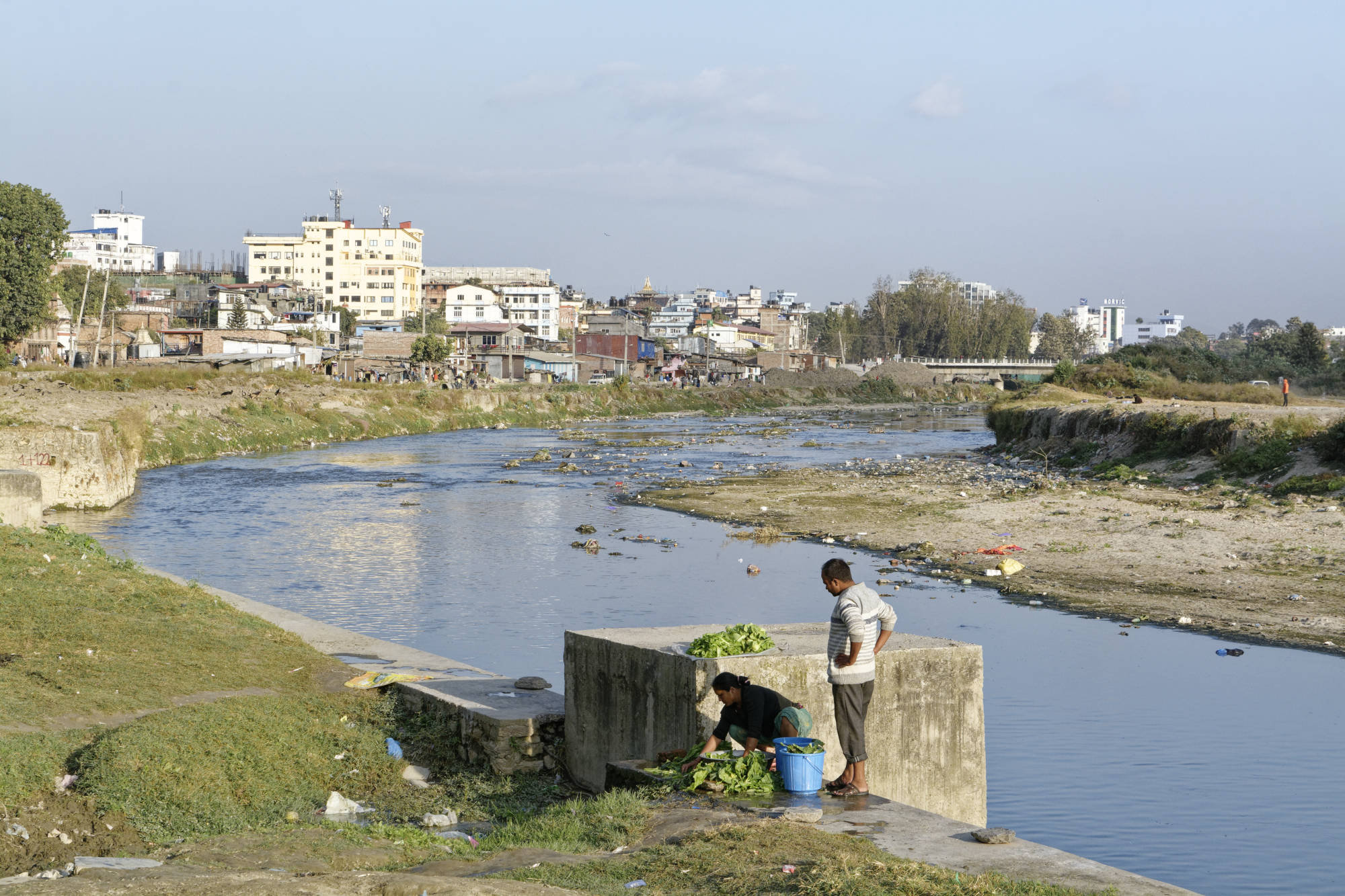 Couple lavant des légumes au bord de la rivière Bagmati à Katmandou