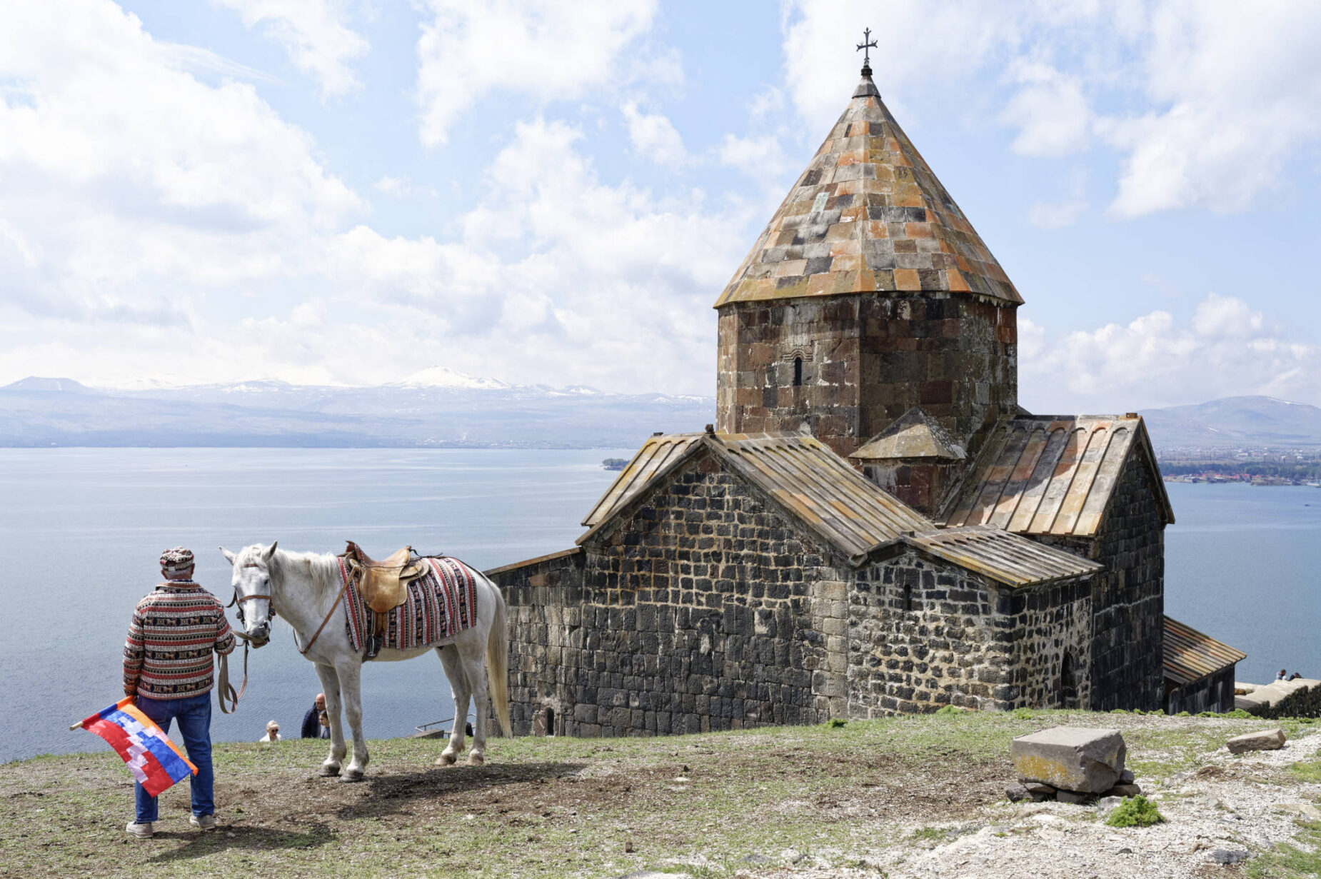 Homme tenant un cheval devant l'église de la péninsule de Sevanavank